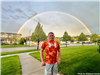 A boy standing under a rainbow. 