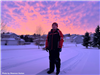 A boy standing in front of a winter sunset. 