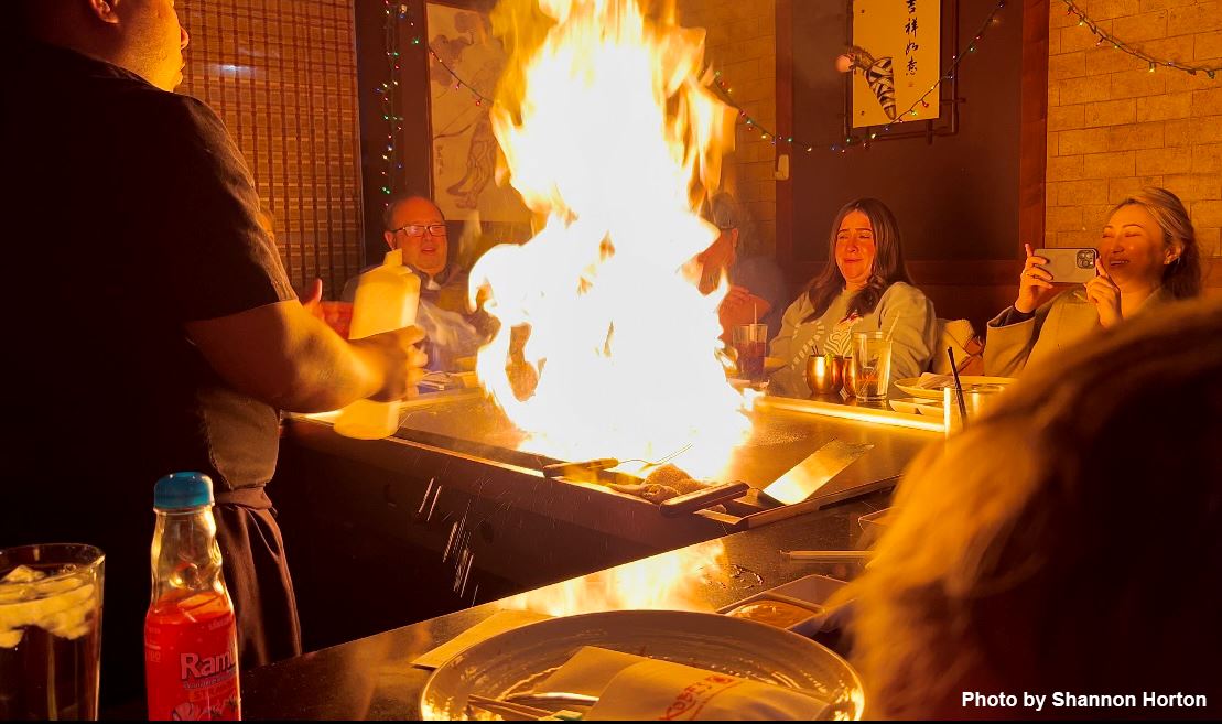 Food preparer uses fire in presentation to seated customers. 