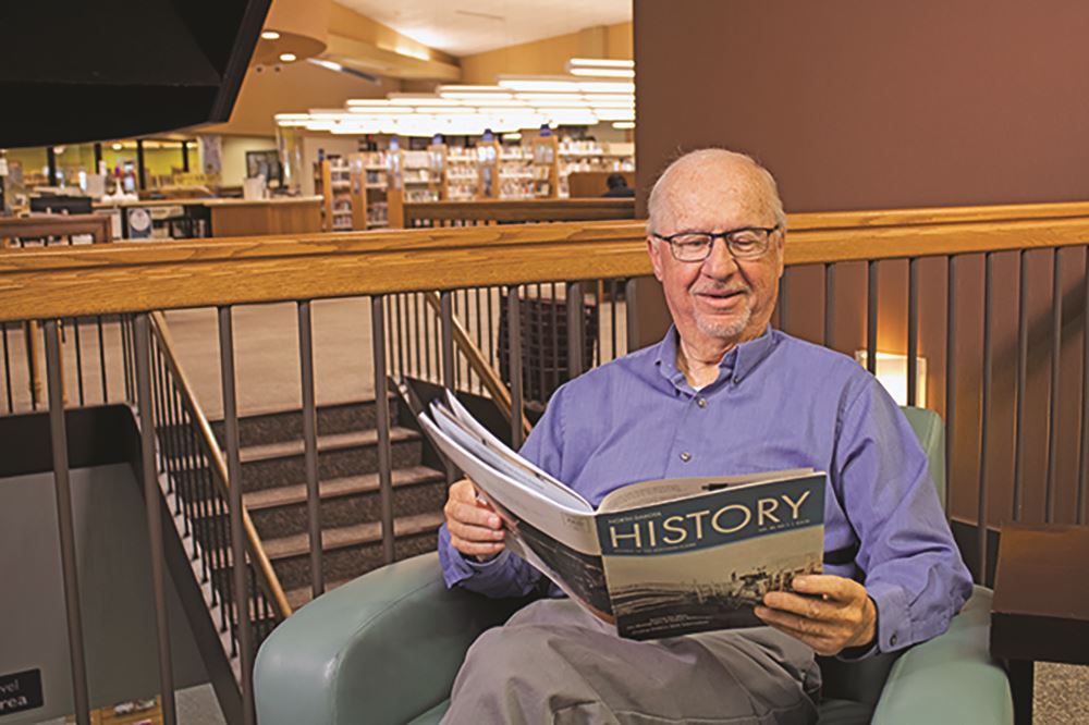 Man sitting in a chair reading a magazine