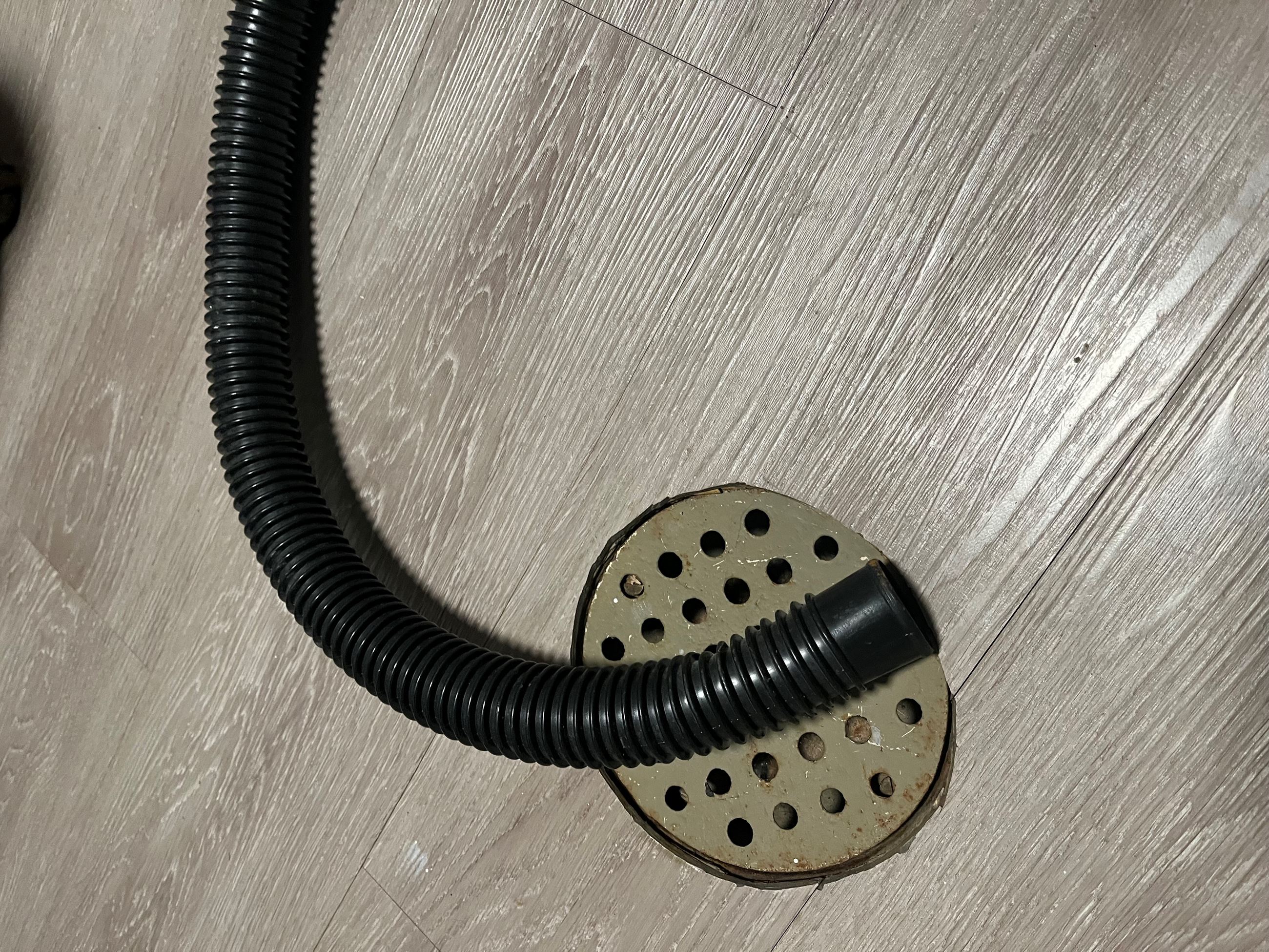 A sump pump discharge hose resting on a floor drain.  
